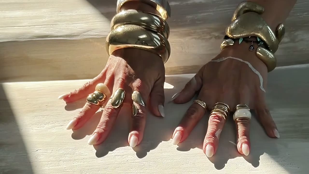 Martina Braun's hands moving over a textured artwork in sunlight
