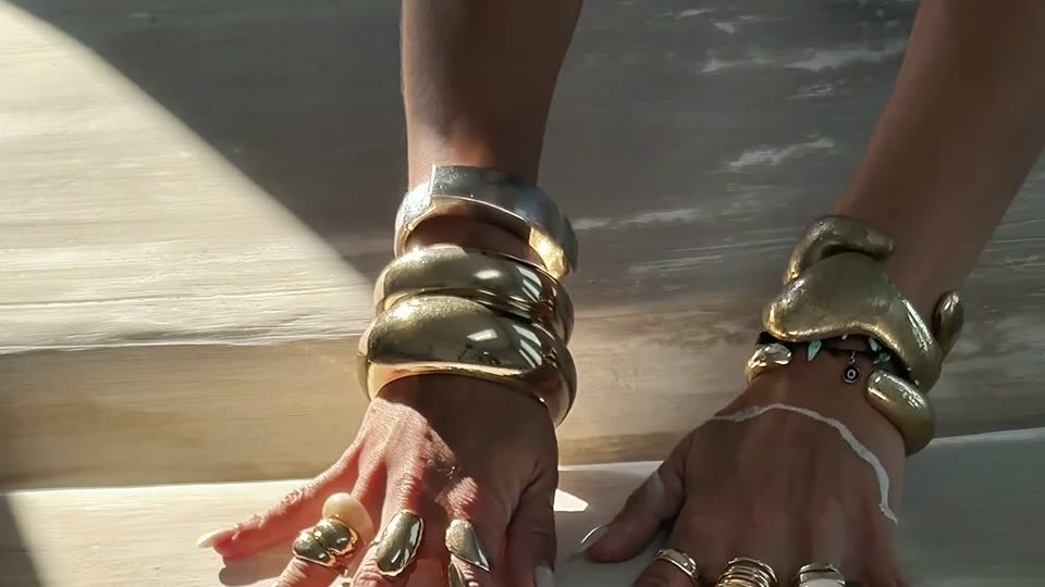 Martina Braun's hands moving over a textured artwork in sunlight